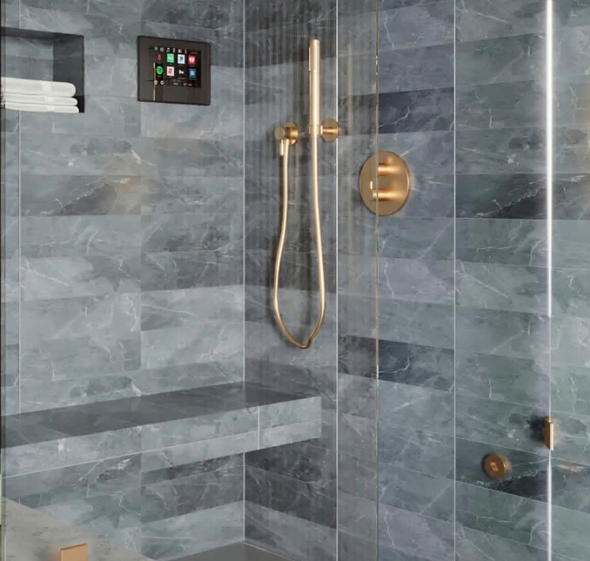 Blue-gray stone-look tile shower with brushed brass hand shower and valve, a built-in bench, niche and digital shower control