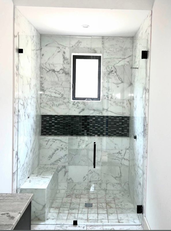 Glass walk-in shower with marble-look tile, a black hexagon tile accent band and a recessed niche