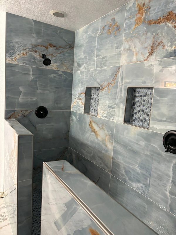Walk-in shower with blue and gold onyx-look stone tile, a built-in bench and a recessed niche